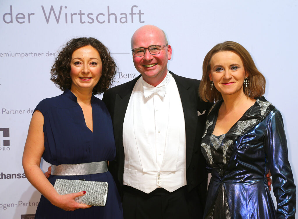 Sigrid Nikutta steht mit blauem Ballkleid neben Markus Voigt, VBKI Chef und Ramona Popp beim 67. Ball der Wirtschaft