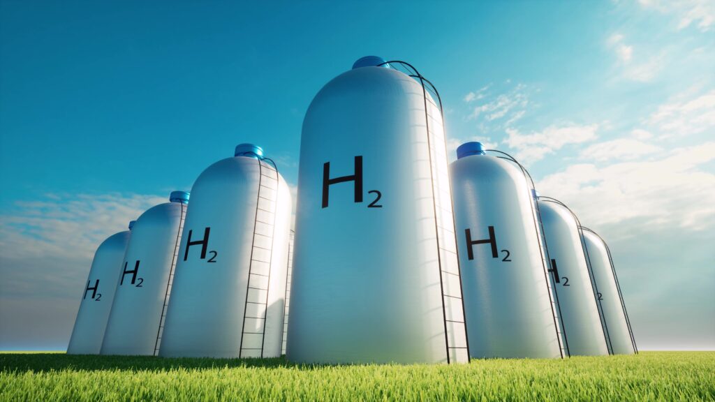 Wasserstoffspeicher in Tanks stehen auf einer Wiese. Dahinter blauer Himmer mit ein paar Wolken