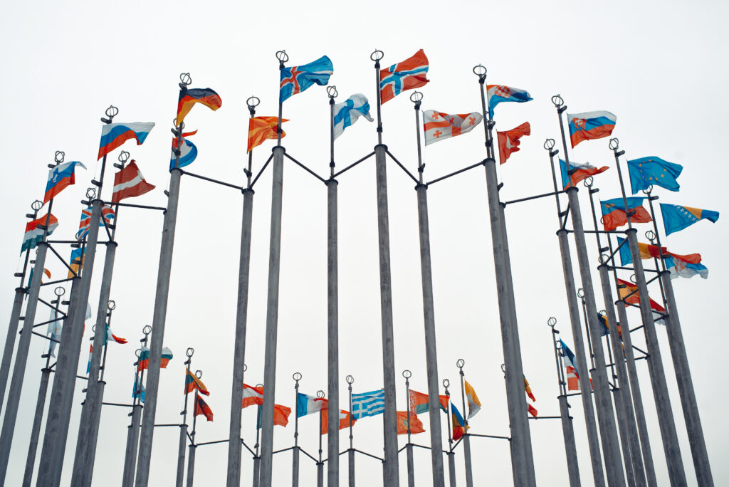 Verschiedene Flaggen von unterschiedlichen Statten auf Masten die im Wind wehen