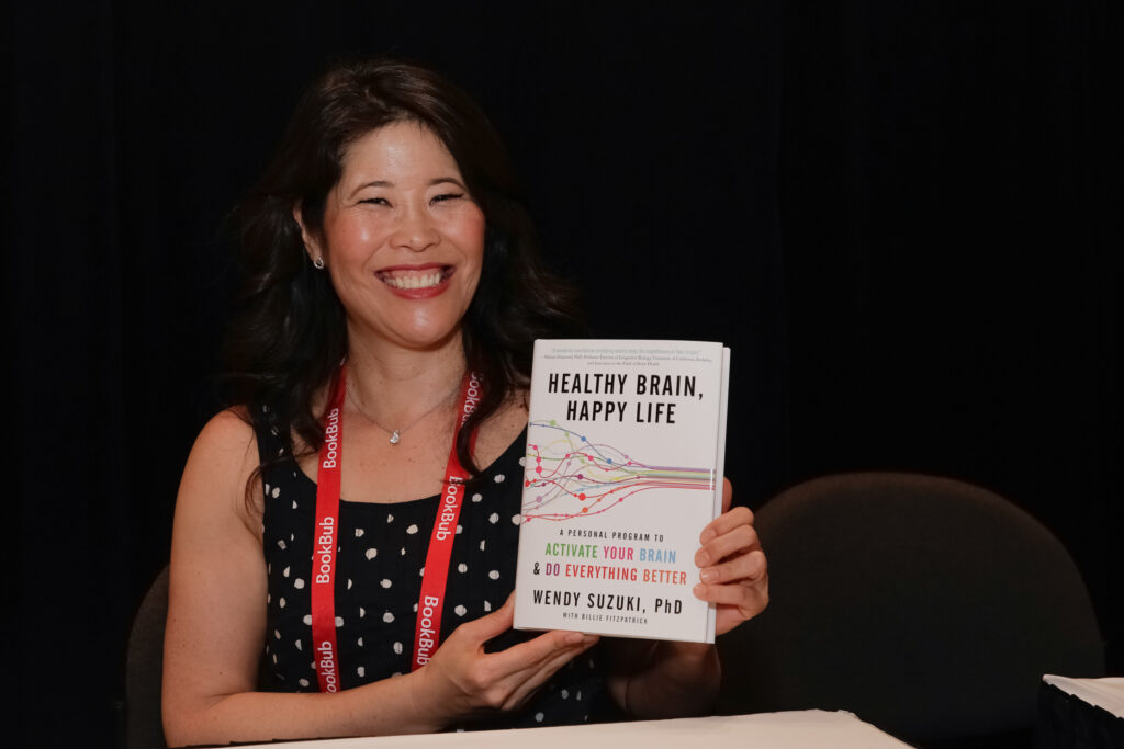 Wendy Suzuki hält ihr Buch in Händen und lächelt in die Kamera