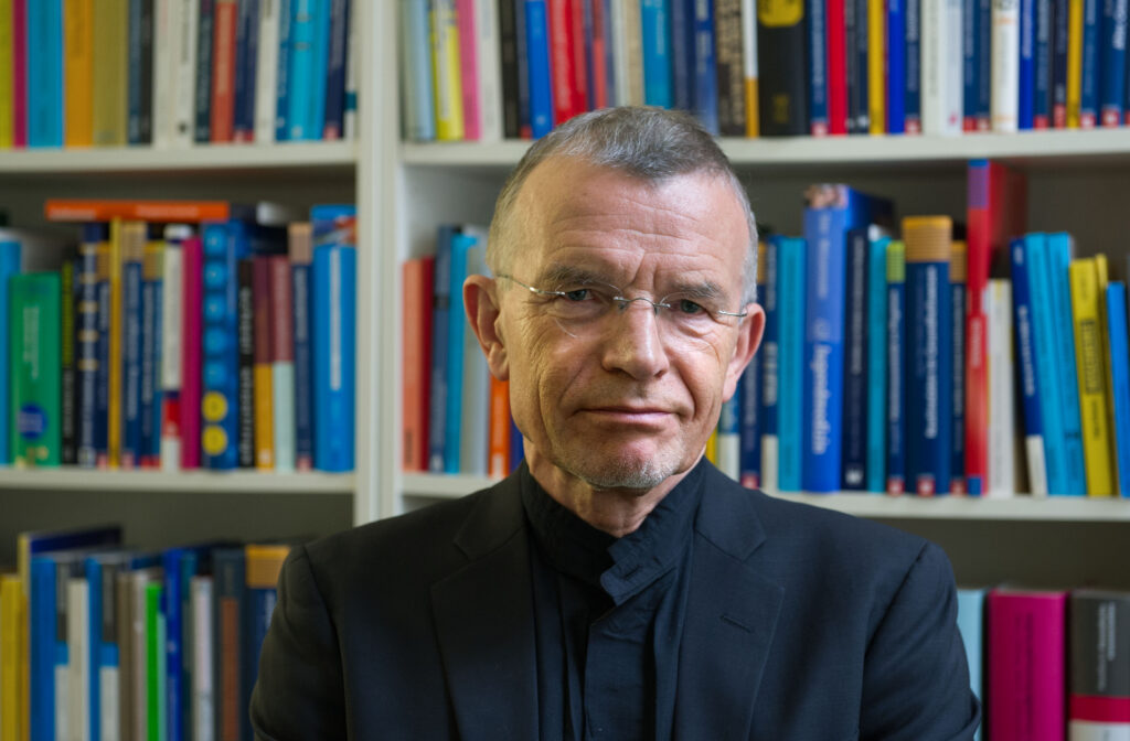 Klaus Hurrelmann steht vor einem Bücherregal und sieht in die Kamera