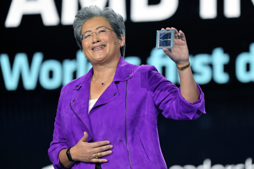 Lisa Su mit violettem Oberteil hält einen Chip hoch