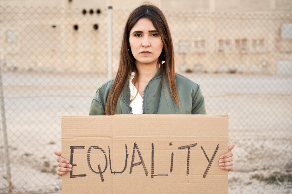 Frau mit einem Karton in der Hand auf dem Equality steht