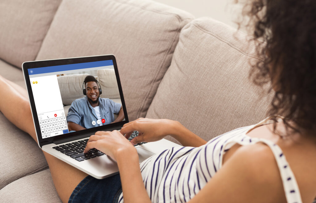 Frau sitzt an einem Computer auf einem Sofa und skyped mit einem Mann 