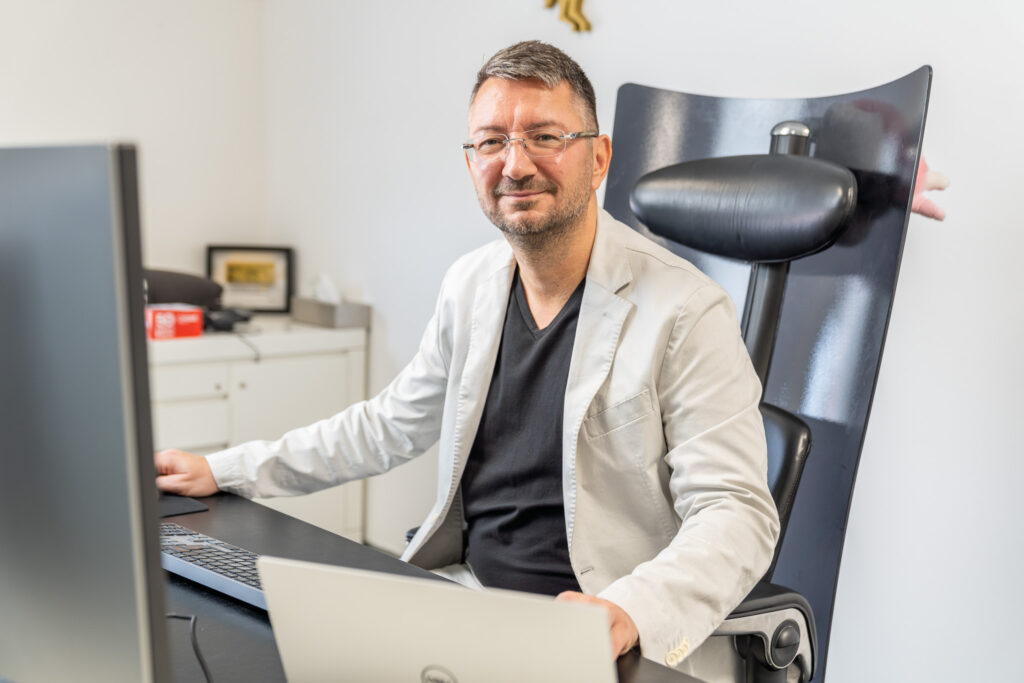 Walter Temmer sitzt vor PCs in seinem Büro am Schreibtisch