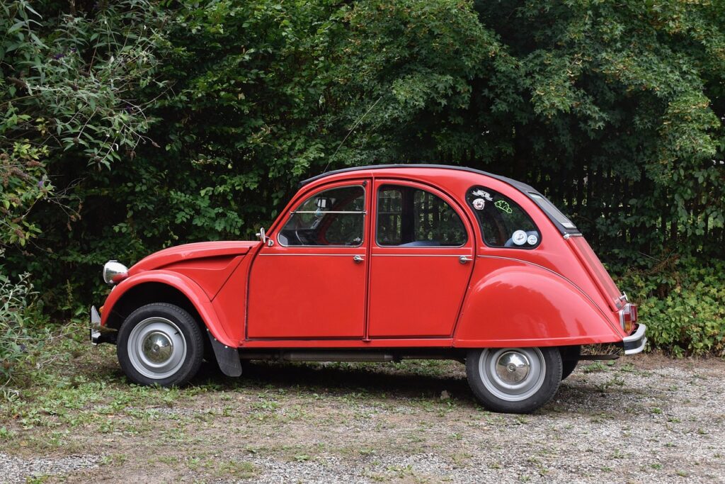 Ein rotes Concept Car zeigt das Design der neuen Elektro-Ente von Citroën mit aufrollbarem Stoffdach in einer hell beleuchteten Ausstellungshalle – Foto: JACLOU-DL / Pixabay