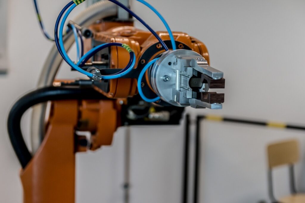 Ein Roboterarm mit sensorbestückten Greifhänden symbolisiert die neue Roboter-KI von Neura Robotics in einer Werkstatt – Foto: jarmoluk / Pixabay